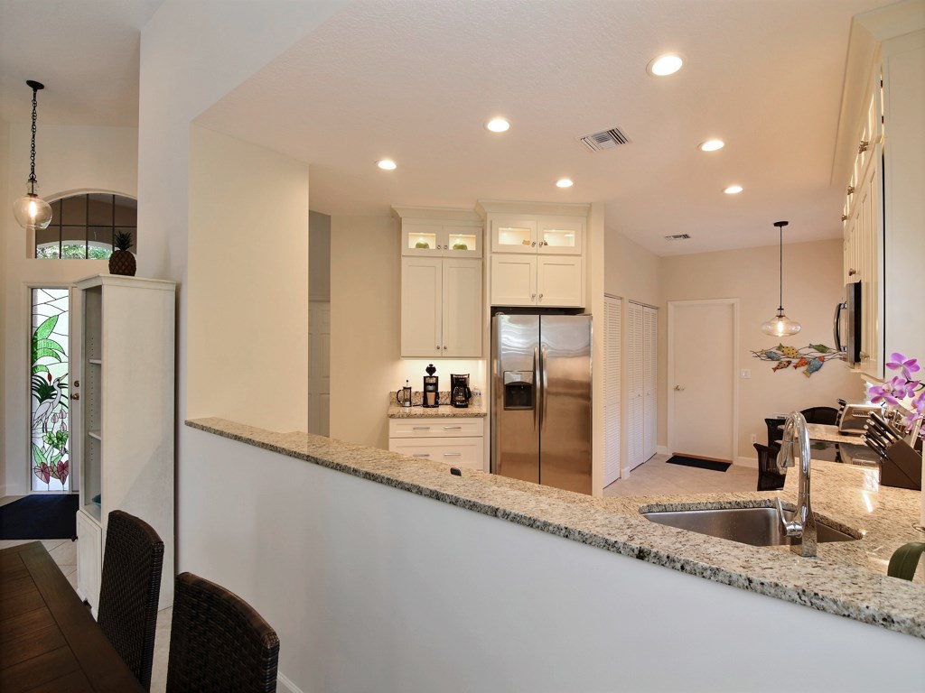 8785 Lakeside Boulevard Vero Beach, FL 32963 - Photo 9 of 36 a kitchen with stainless steel appliances kitchen island granite countertop a refrigerator and a sink