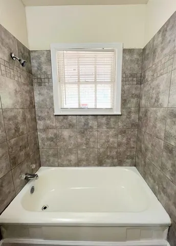 an empty room with wooden floor a ceiling fan and windows