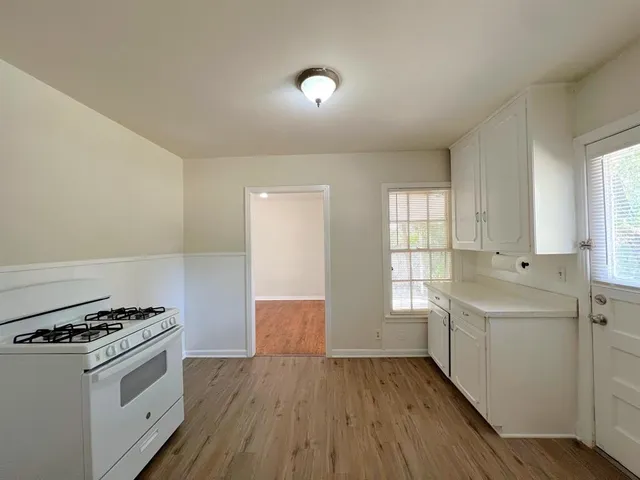 a view of a hallway with wooden floor and cabinet