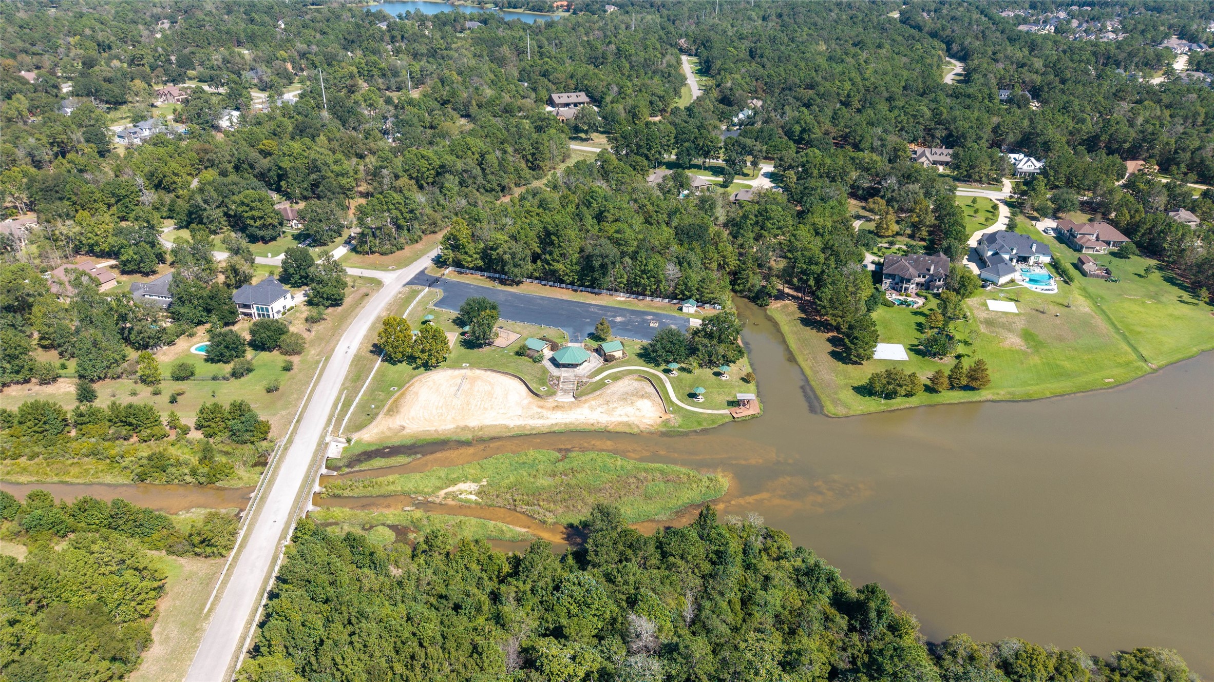 0 Ridgelake Court Montgomery, TX 77316 - Photo 23 of 29 Expansive wooded landscape with a serene lake, surrounded by spacious homes and lush greenery, offering a tranquil and private setting.
