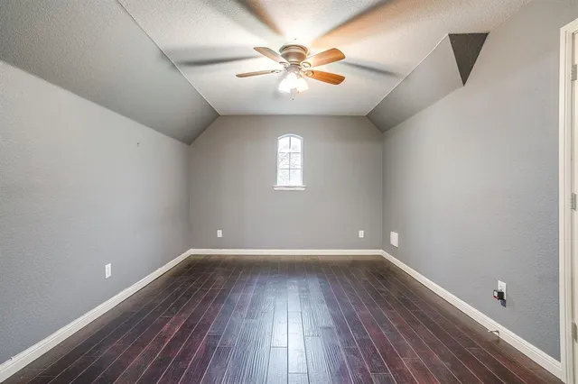 an empty room with wooden floor chandelier fan and windows