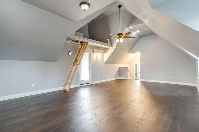 an empty room with wooden floor chandelier fan and windows