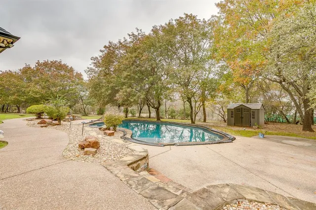 swimming pool with outdoor seating and trees in the background