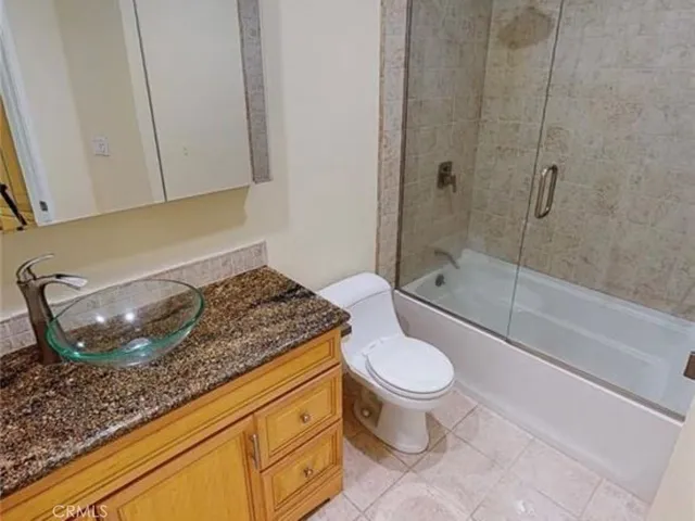 a bathroom with a granite countertop toilet and a sink