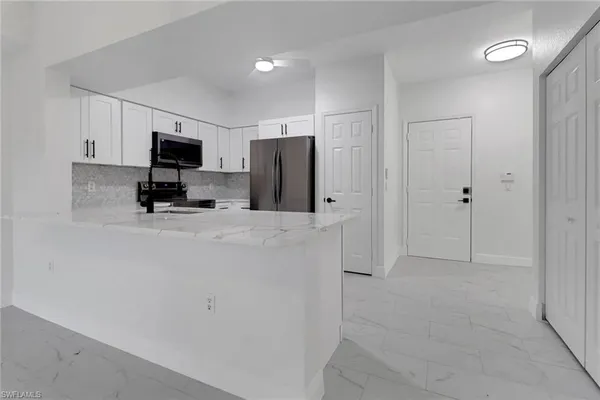 a kitchen with stainless steel appliances a refrigerator a microwave a sink and a refrigerator