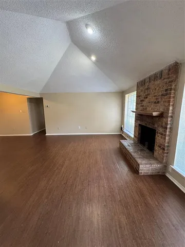 an empty room with wooden floor and fireplace