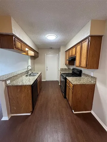 a kitchen with stainless steel appliances granite countertop a stove a sink dishwasher and a refrigerator with wooden floor