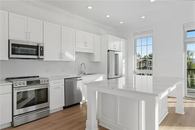 a kitchen with kitchen island granite countertop a stove a sink and a microwave