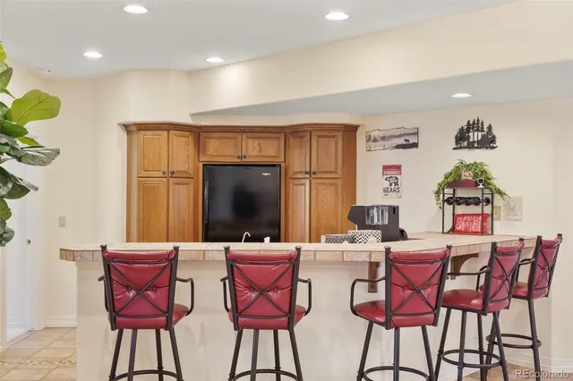 a dining room with stainless steel appliances kitchen island granite countertop a dining table chairs and a refrigerator