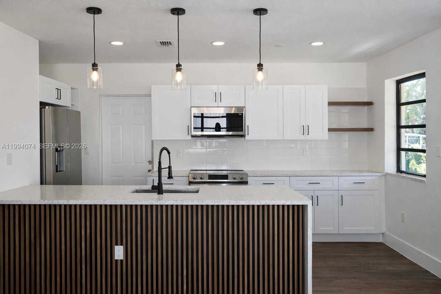 1950 Northwest 57th Street, Unit 1950 Miami, FL 33142 - Photo 3 of 10 a kitchen with stainless steel appliances granite countertop a sink a refrigerator and a microwave