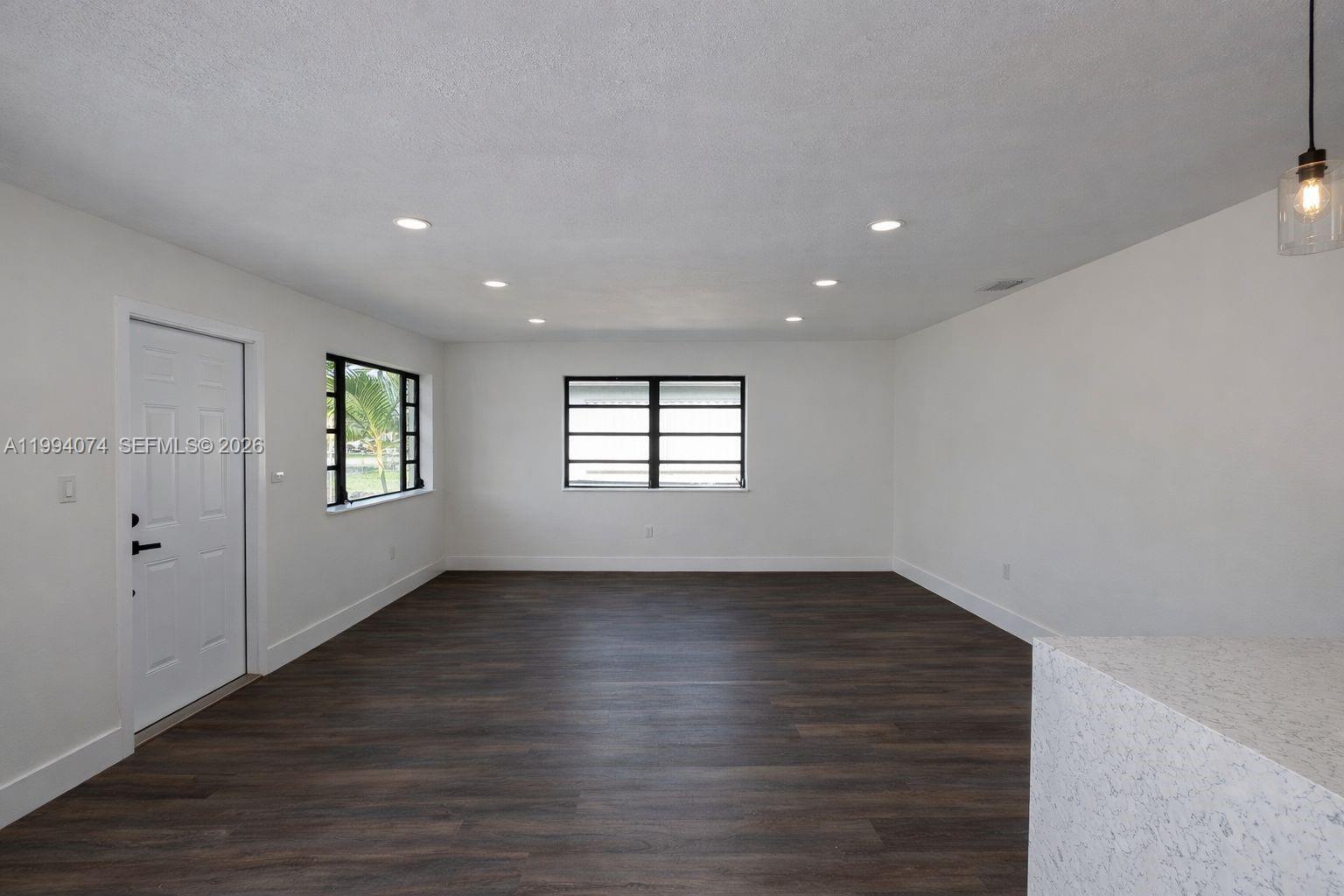 1950 Northwest 57th Street, Unit 1950 Miami, FL 33142 - Photo 5 of 10 an empty room with wooden floor and windows