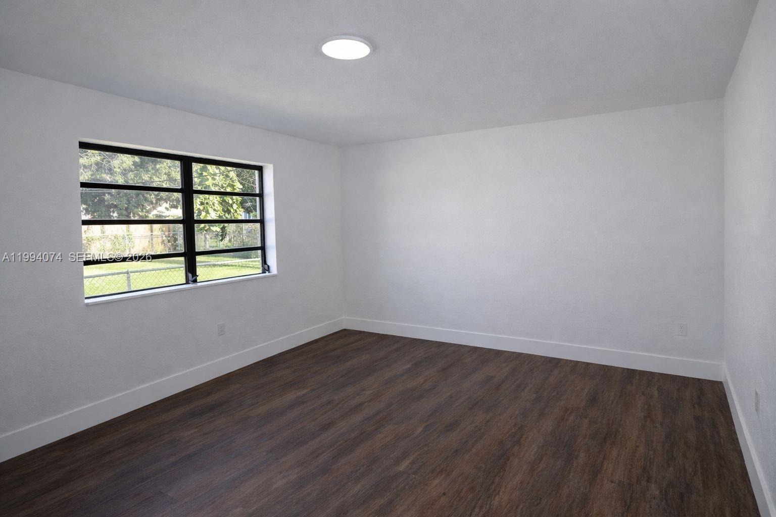1950 Northwest 57th Street, Unit 1950 Miami, FL 33142 - Photo 8 of 10 an empty room with wooden floor and windows