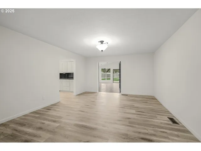 a view of an empty room with a window and wooden floor