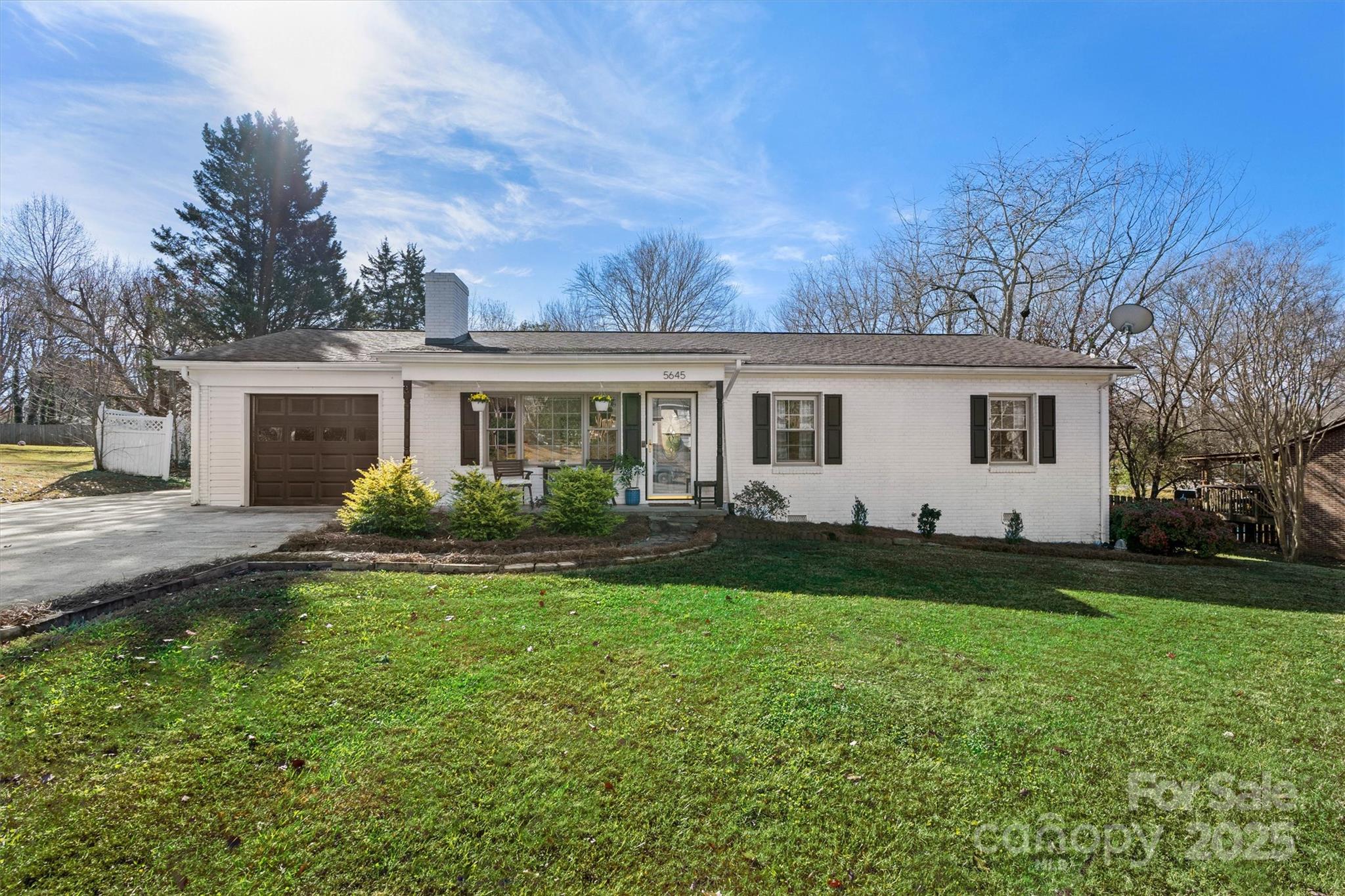 a front view of a house with garden and trees