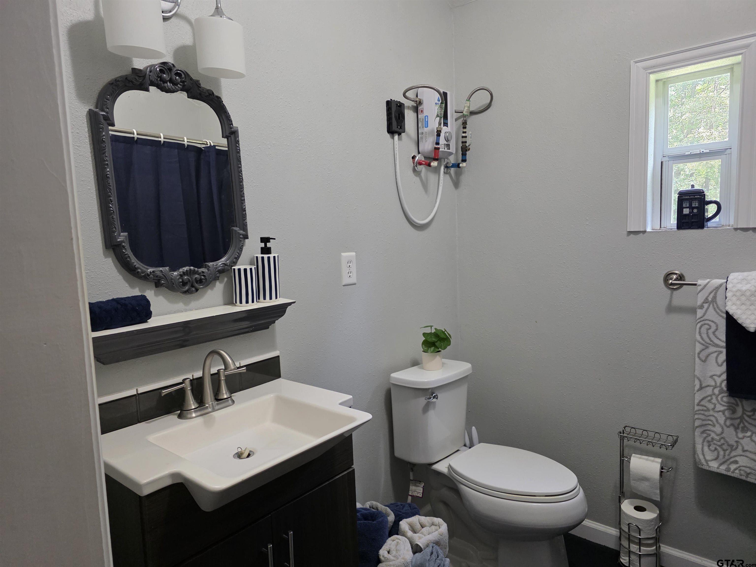6170 Highway 271 Mount Pleasant, TX 75455 - Photo 42 of 43 a bathroom with a toilet a sink and mirror