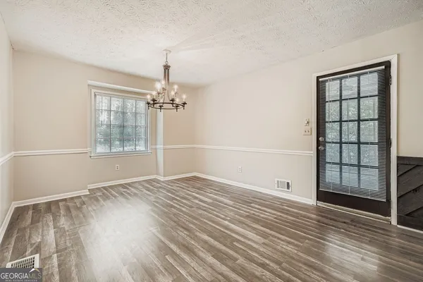 an empty room with wooden floor cabinet and windows