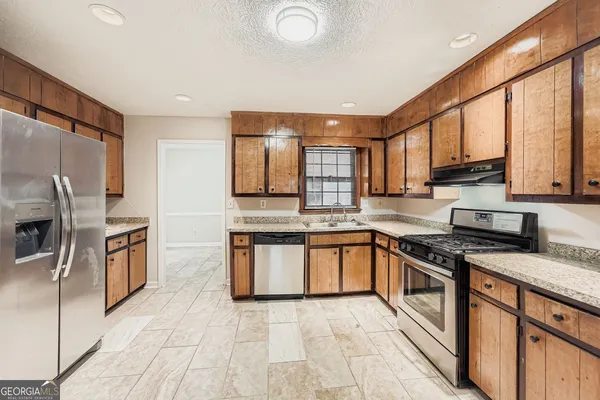 a kitchen with stainless steel appliances granite countertop a stove top oven a sink and dishwasher
