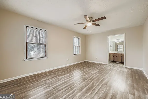 a view of empty room with wooden floor and fan