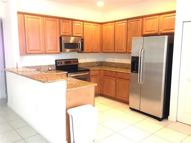 a kitchen with stainless steel appliances granite countertop a refrigerator a stove a sink and dishwasher