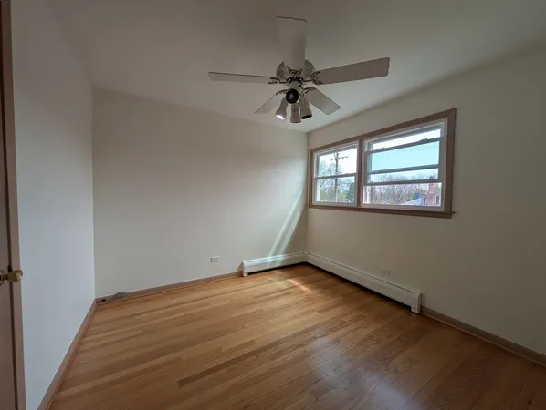an empty room with wooden floor fan and windows