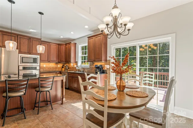 a kitchen with stainless steel appliances granite countertop a stove a refrigerator a kitchen island a table and chairs