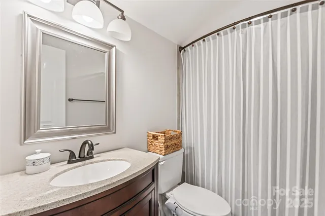 a bathroom with a granite countertop bathtub sink vanity mirror and toilet