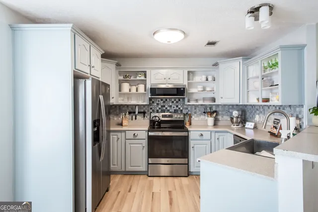 a kitchen with stainless steel appliances granite countertop a stove top oven a sink and a refrigerator