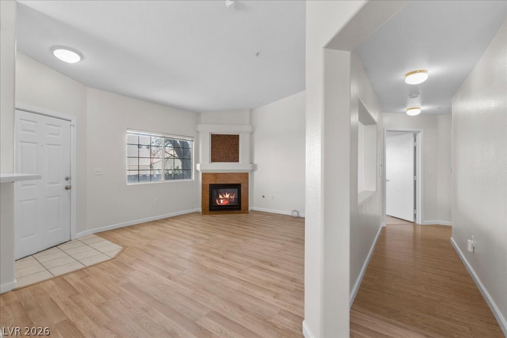 1881 West Alexander Road, Unit 1037 North Las Vegas, NV 89032 - Photo 9 of 31 A corner fireplace adds warmth to this versatile living area, featuring light wood flooring and a large window.