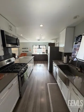 a kitchen with stainless steel appliances granite countertop a stove top oven a sink dishwasher and a refrigerator