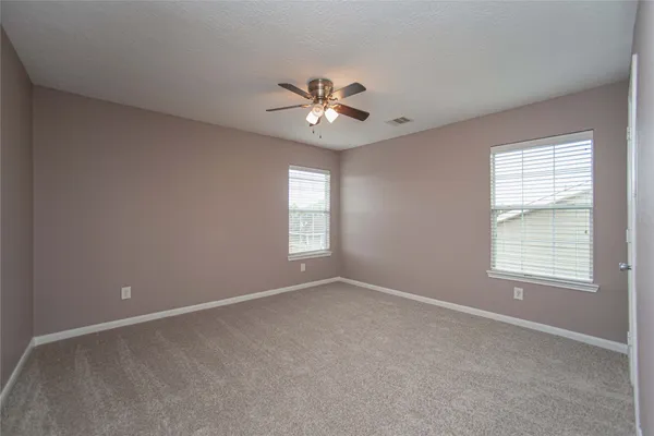 an empty room with windows and ceiling fan