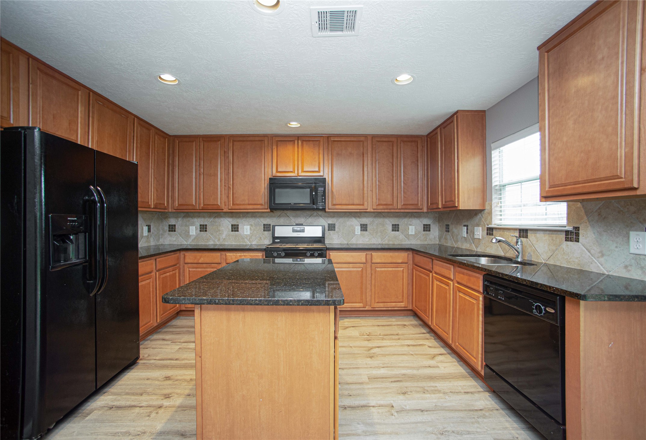 29314 Legends Bluff Drive Spring, TX 77386 - Photo 6 of 26 a kitchen with granite countertop wooden cabinets a refrigerator and a sink