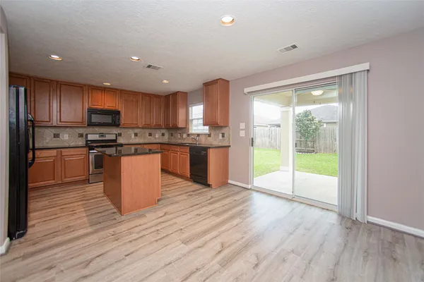 a kitchen with stainless steel appliances granite countertop a stove top oven a sink and a refrigerator