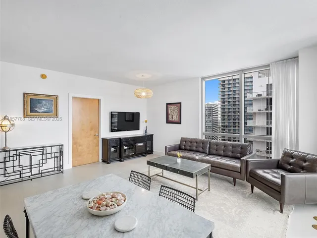 a view of kitchen with stainless steel appliances granite countertop a stove a sink a refrigerator white cabinets and couches