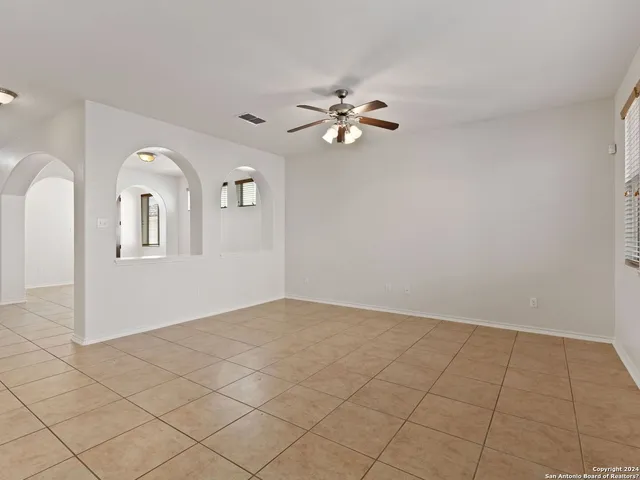 an empty room with wooden floor chandelier fan and windows