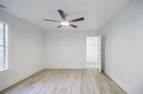 an empty room with wooden floor and ceiling fan