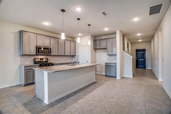 a large kitchen with stainless steel appliances kitchen island a large counter top a stove a sink cabinets and a refrigerator