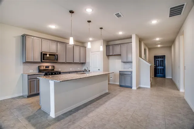 a large kitchen with stainless steel appliances kitchen island a large counter top a stove a sink cabinets and a refrigerator