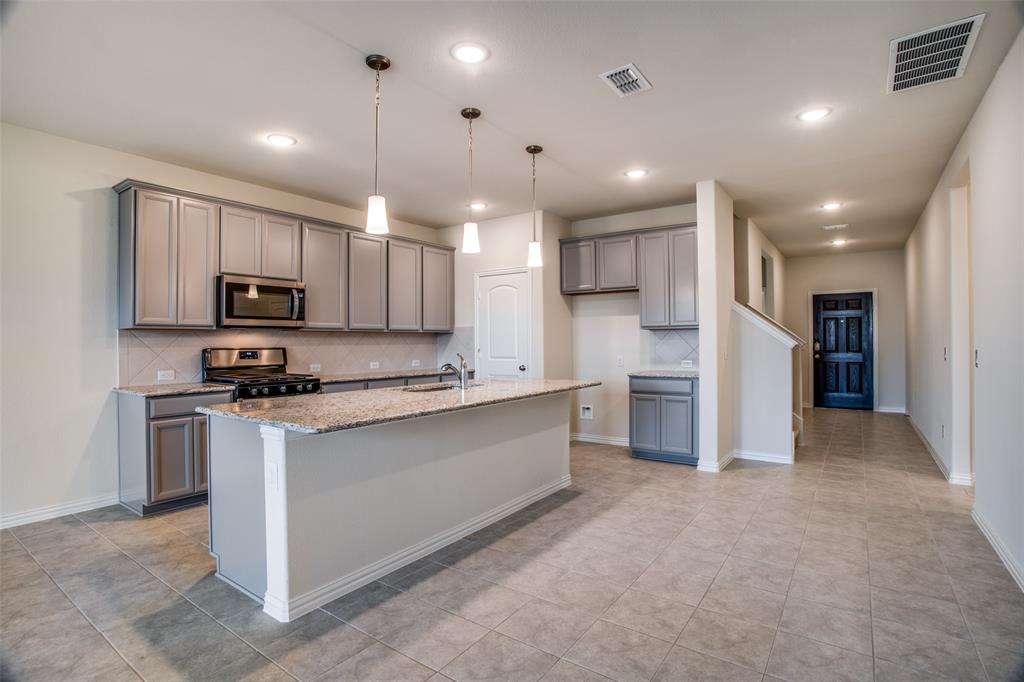 1237 Sharp Street Anna, TX 75409 - Photo 3 of 18 a large kitchen with stainless steel appliances kitchen island a large counter top a stove a sink cabinets and a refrigerator