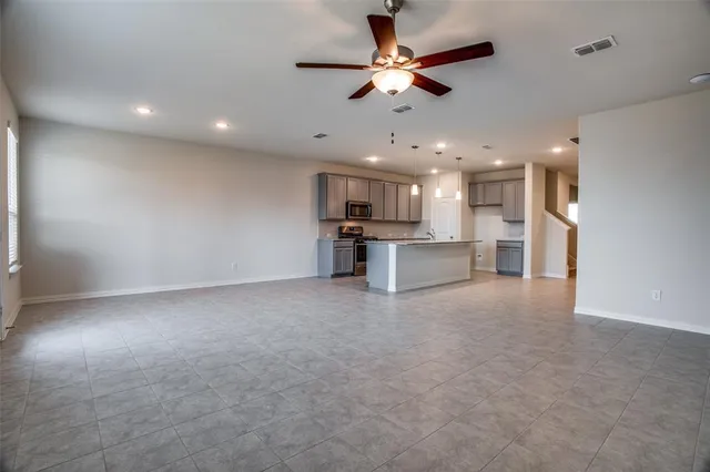 an open kitchen with a refrigerator and a ceiling fan