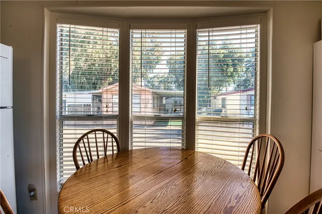 a dining room with stainless steel appliances granite countertop a refrigerator a sink dishwasher a dining table and chairs with wooden floor