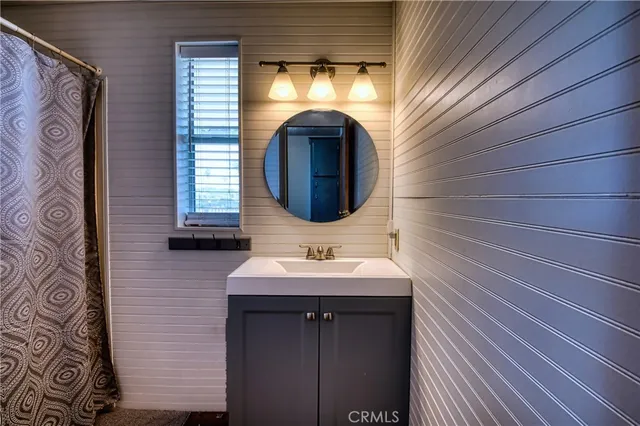 a view of a hallway with wooden floor and a bathroom