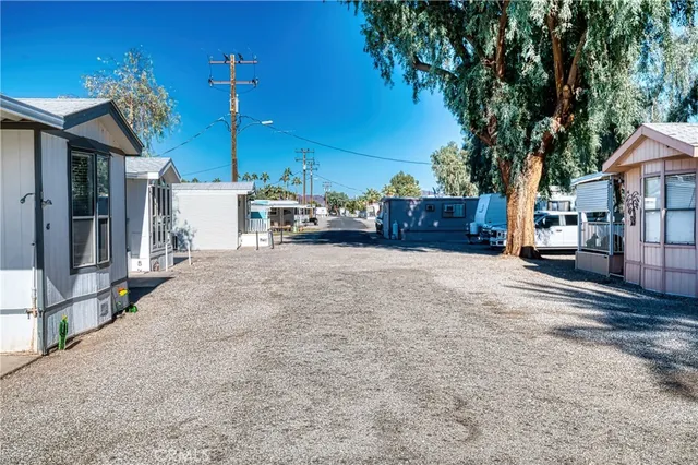 a view of a patio with couches table and chairs under an umbrella with large trees