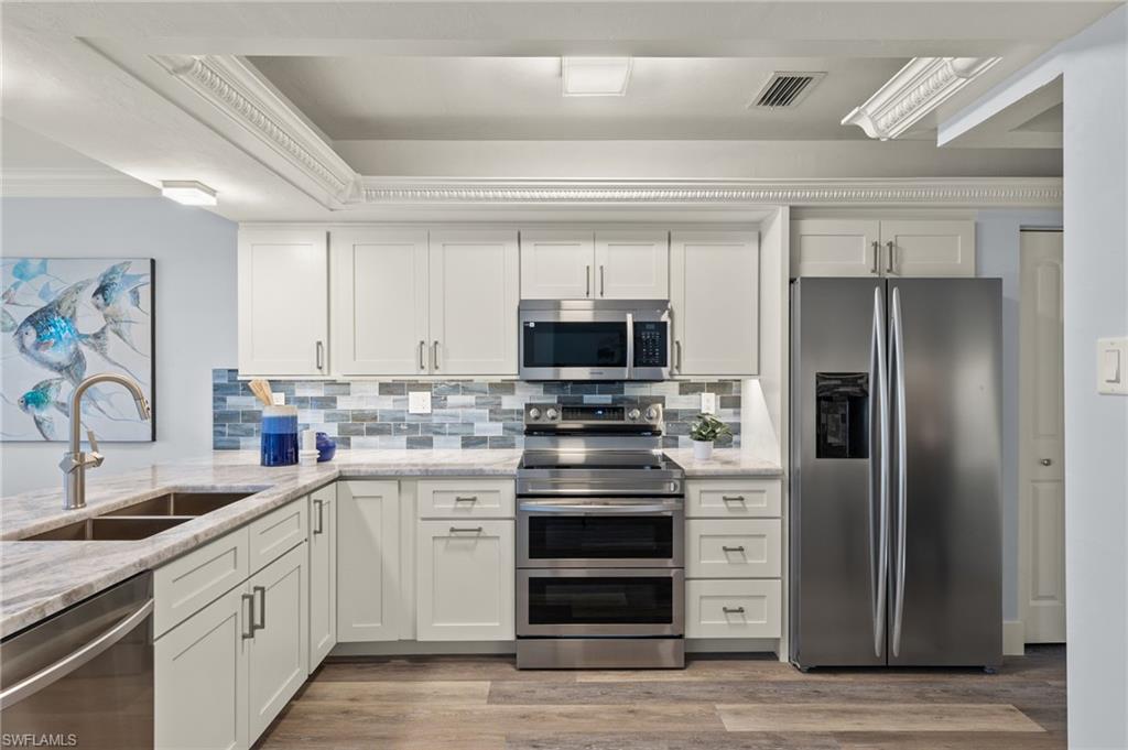 2796 Clipper Way Naples, FL 34104 - Photo 3 of 36 Kitchen with sink, light stone countertops, appliances with stainless steel finishes, light hardwood / wood-style floors, and white cabinetry