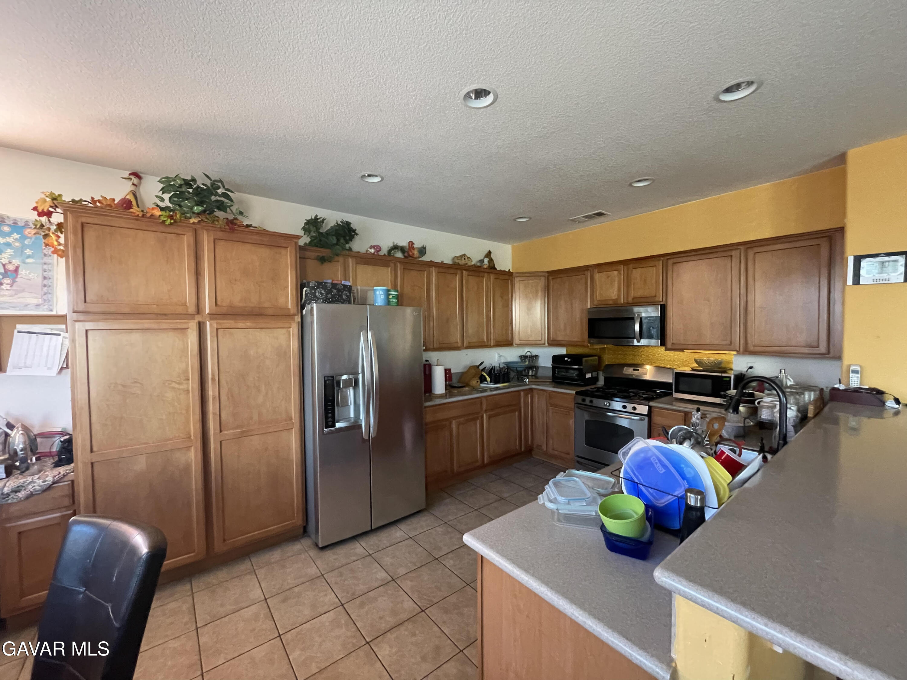 3303 Arious Way Lancaster, CA 93536 - Photo 39 of 43 a kitchen with stainless steel appliances wooden cabinets a stove top oven a sink and a dining table