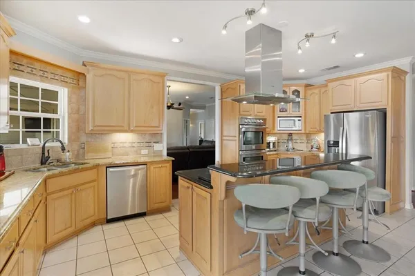 a kitchen with stainless steel appliances granite countertop a sink a stove a refrigerator island and chairs