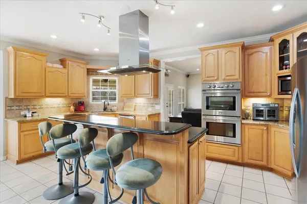 a large kitchen with cabinets chairs and stainless steel appliances
