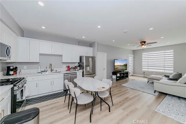 a kitchen with stainless steel appliances kitchen island granite countertop a stove a sink a refrigerator and white cabinets with wooden floor