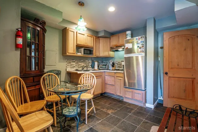 a kitchen with stainless steel appliances a refrigerator a stove a dining table and chairs