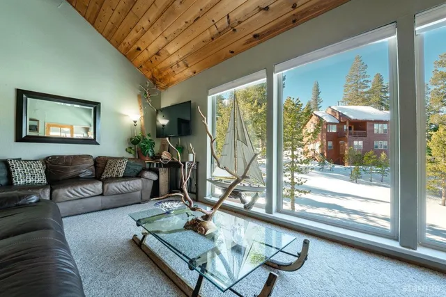 a living room with furniture a flat screen tv and a floor to ceiling window