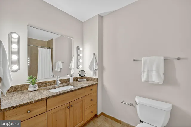 a bathroom with a granite countertop sink a toilet and a mirror